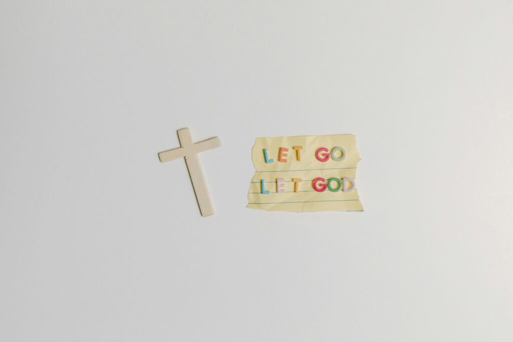 A simple and powerful image featuring a cross alongside the inspiring quote 'Let Go Let God' on paper.